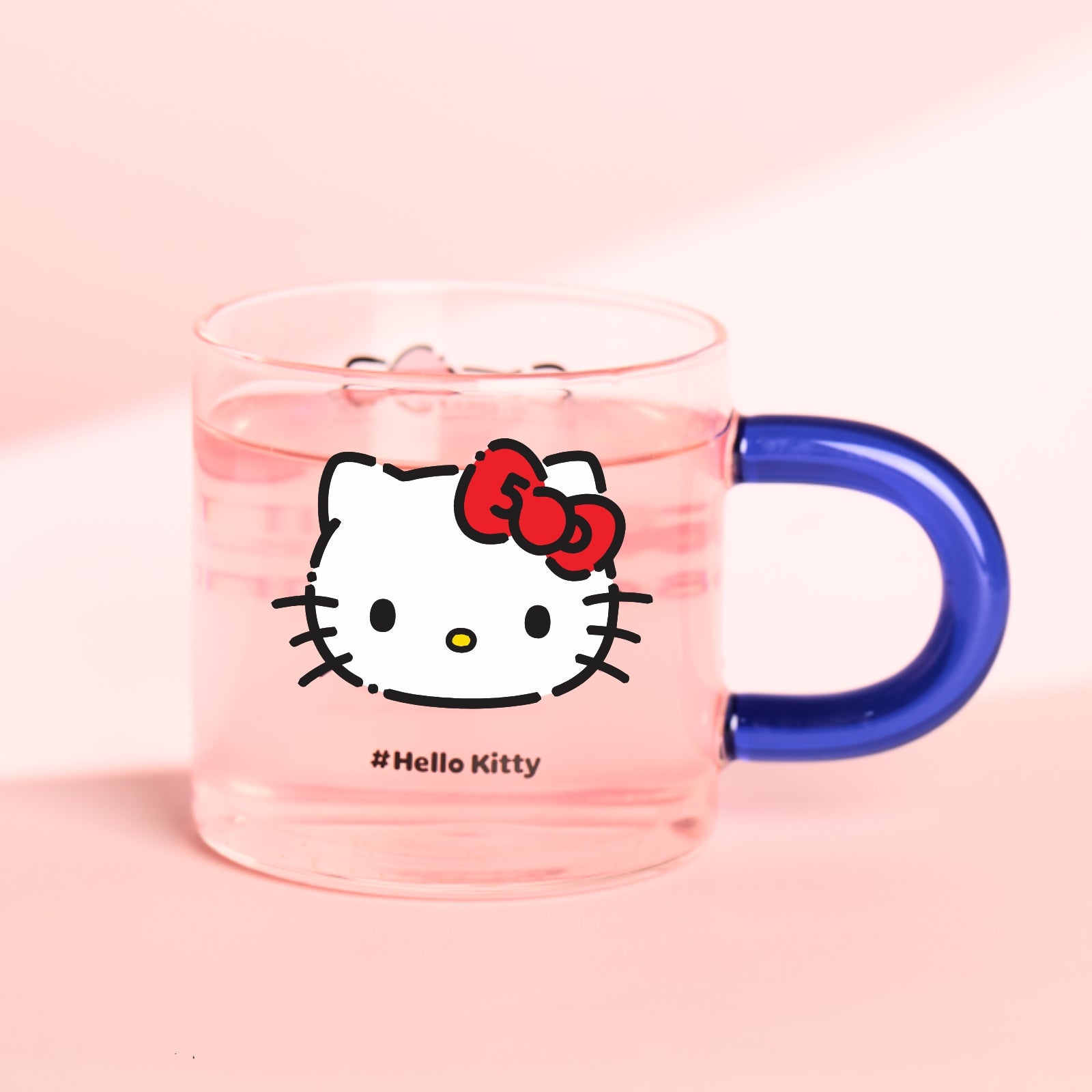 A glass mug with a Hello Kitty character design featuring a red bow on the front, complete with a blue handle.
